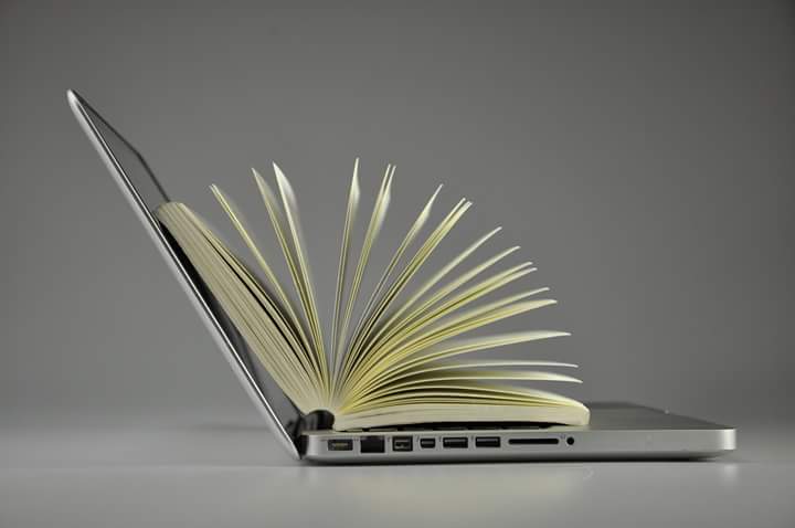 Aufgeklappter Laptop mit Buch